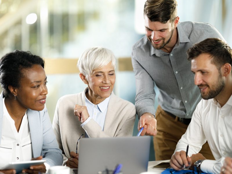 Group of happy entrepreneurs cooperating while reading an e-mail on a computer in the office.